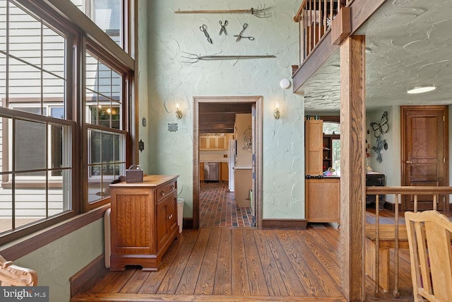 interior space featuring a textured ceiling, a textured wall, hardwood / wood-style flooring, and baseboards