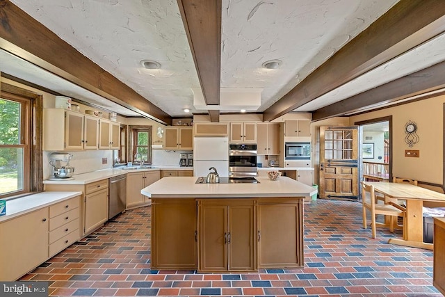 kitchen featuring brick floor, beam ceiling, light countertops, appliances with stainless steel finishes, and a sink