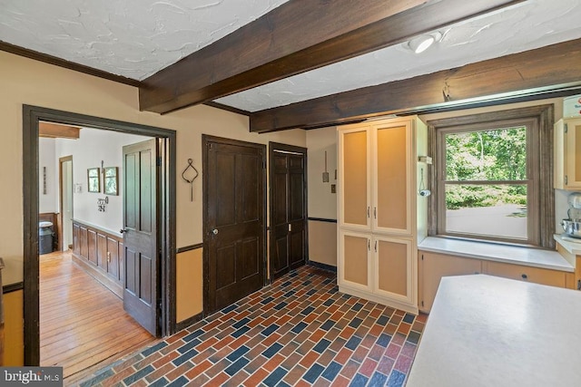 kitchen featuring brick floor, light countertops, and beamed ceiling