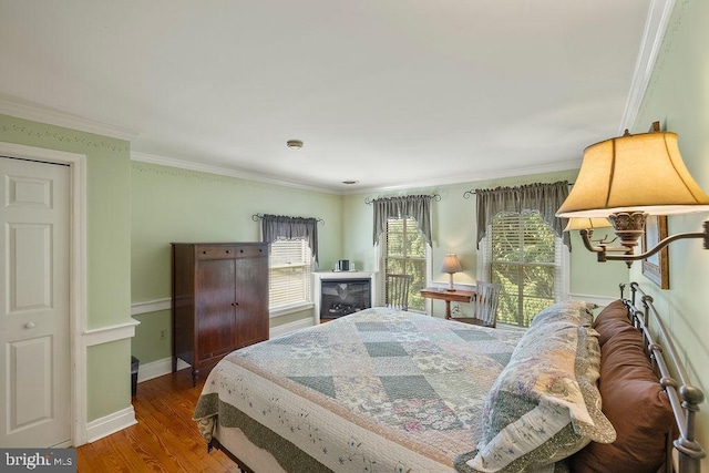 bedroom with baseboards, wood finished floors, and crown molding