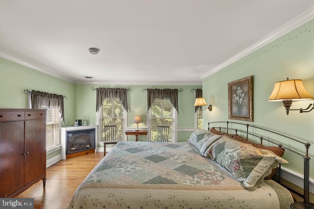 bedroom featuring ornamental molding, baseboards, and wood finished floors