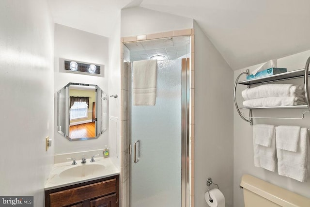 bathroom featuring toilet, a stall shower, vanity, and lofted ceiling