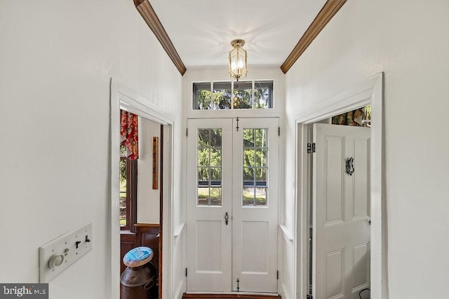 doorway with french doors, an inviting chandelier, and crown molding