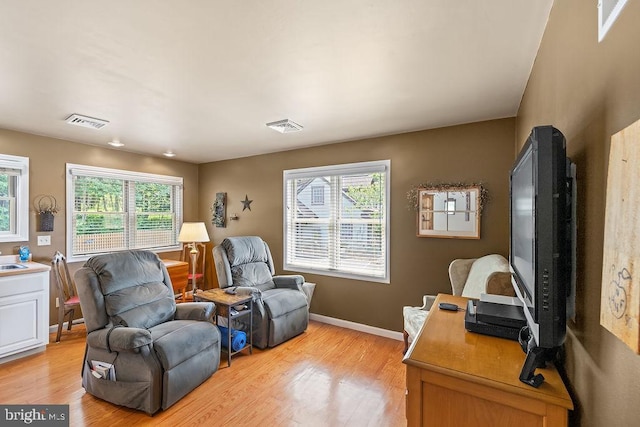 sitting room with a wealth of natural light, visible vents, and light wood-style floors