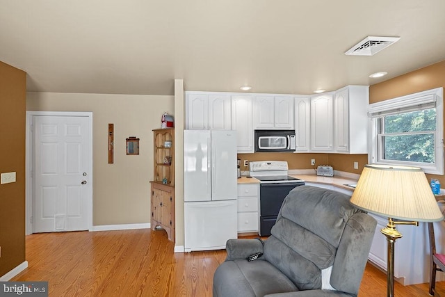 kitchen featuring visible vents, electric stove, freestanding refrigerator, light countertops, and white cabinetry