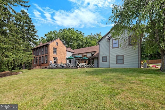 rear view of property with central AC and a lawn