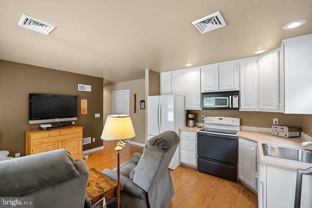 kitchen featuring electric range, visible vents, a sink, and freestanding refrigerator