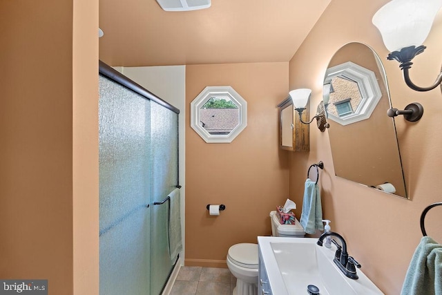 bathroom featuring toilet, a stall shower, tile patterned flooring, and a sink