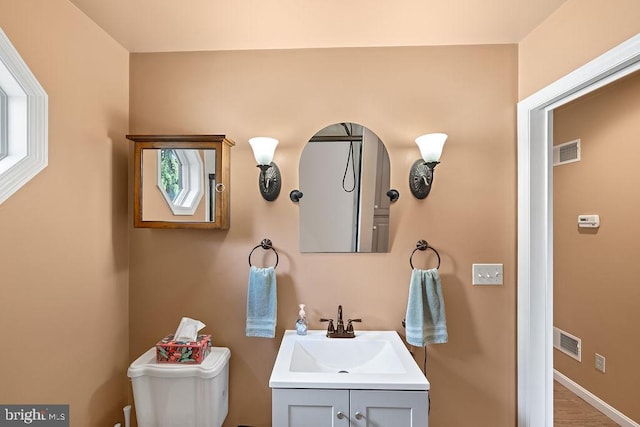 bathroom with baseboards, visible vents, vanity, and toilet