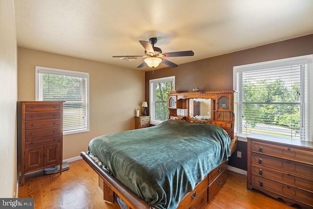 bedroom featuring light wood-type flooring, baseboards, and a ceiling fan