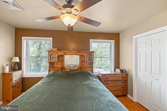 bedroom with light wood-style floors, visible vents, baseboards, and a ceiling fan