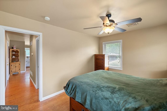 bedroom with a ceiling fan, light wood-style flooring, visible vents, and baseboards