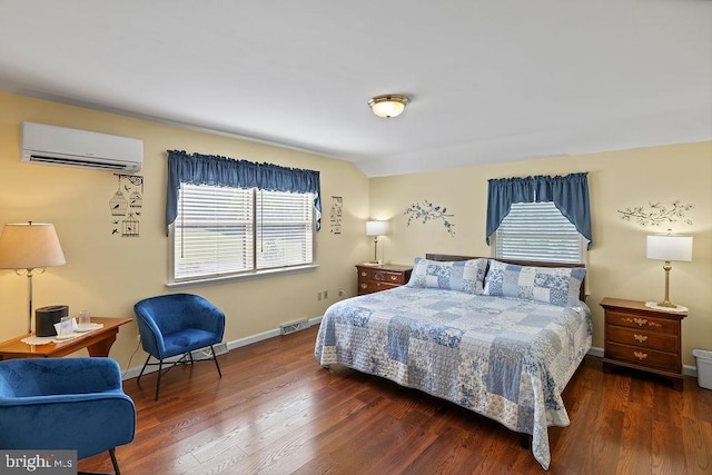 bedroom with an AC wall unit, baseboards, and wood finished floors