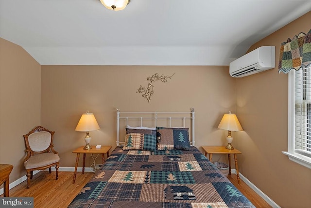 bedroom featuring baseboards, vaulted ceiling, wood finished floors, and a wall mounted air conditioner