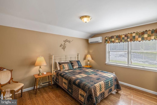 bedroom featuring lofted ceiling, a wall unit AC, baseboards, and wood finished floors