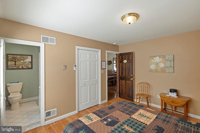 bedroom with baseboards, visible vents, and wood finished floors