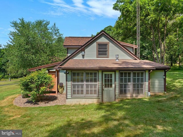 back of property with a yard and a shingled roof