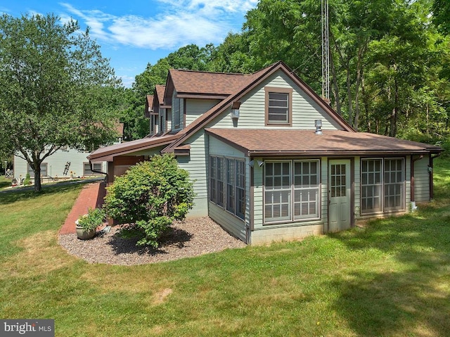 back of property featuring a shingled roof, a yard, and a chimney