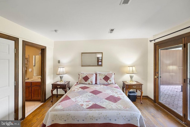 bedroom with ensuite bathroom, light wood finished floors, a sink, and visible vents