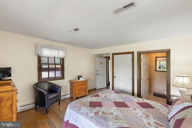 bedroom featuring baseboard heating, wood finished floors, and visible vents