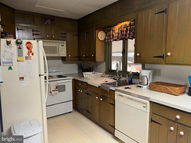 kitchen with white appliances, light countertops, dark brown cabinets, light floors, and a sink