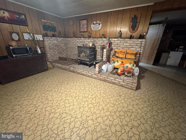 living room with ornamental molding, wood walls, and a wood stove