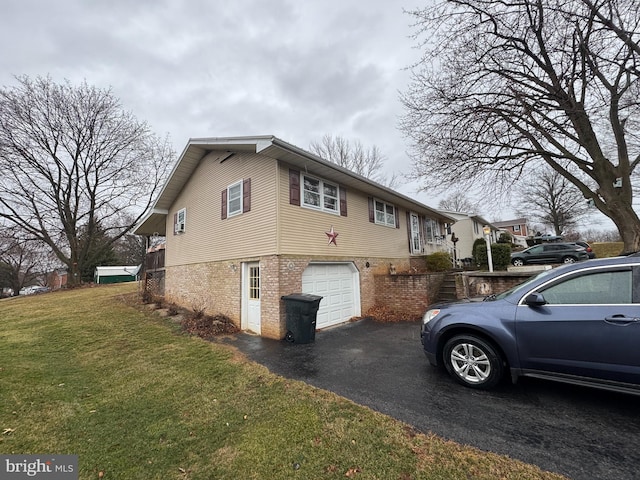 view of home's exterior featuring an attached garage, aphalt driveway, a lawn, and brick siding