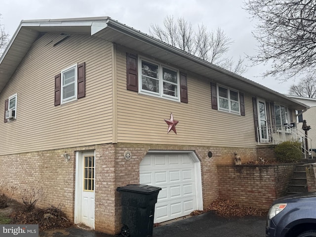 view of side of home featuring an attached garage and brick siding