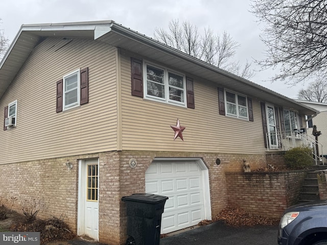 view of side of home featuring a garage and brick siding