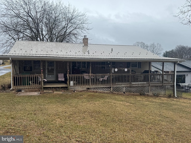 rear view of house with metal roof, a lawn, and a chimney