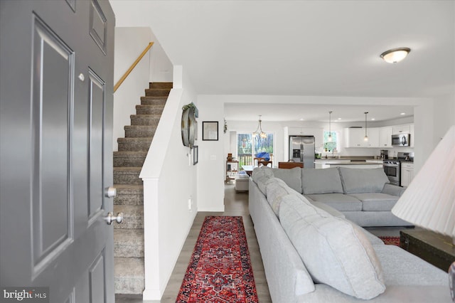 living area featuring stairs, a notable chandelier, and recessed lighting