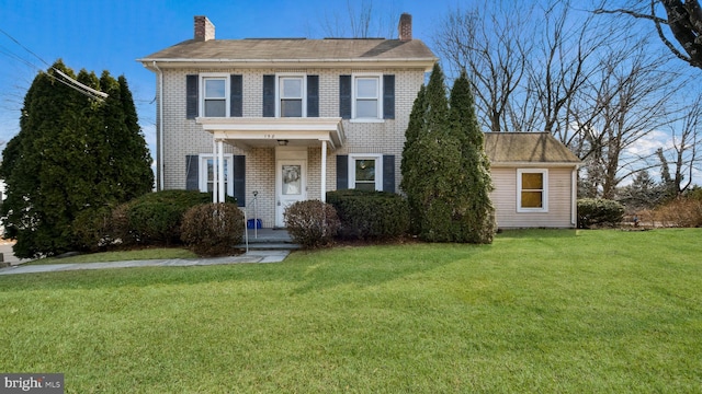 view of front of property with a chimney, a front lawn, and brick siding