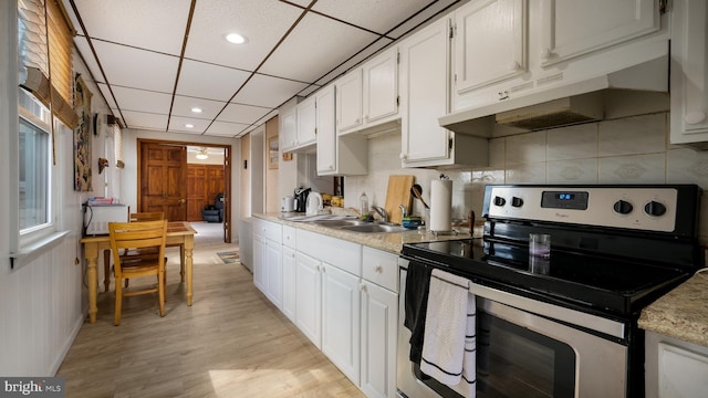 kitchen with light countertops, white cabinetry, a sink, under cabinet range hood, and stainless steel electric range