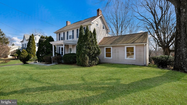 view of front of home featuring a porch, a chimney, and a front yard