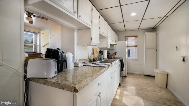 kitchen with a wealth of natural light, white cabinetry, ceiling fan, and a paneled ceiling