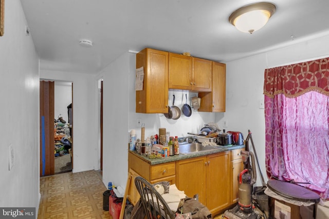 kitchen featuring brown cabinetry, a sink, and light floors