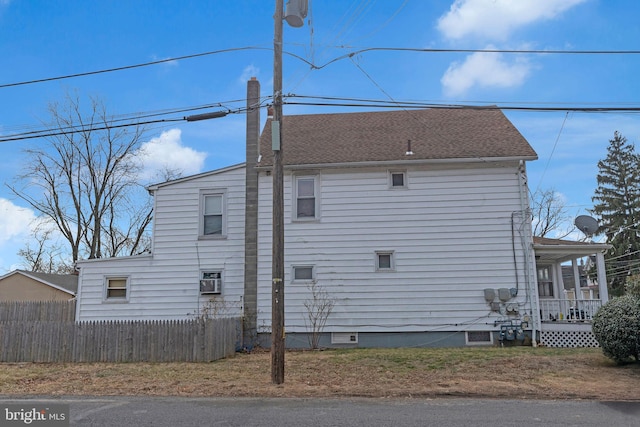 view of home's exterior featuring crawl space, roof with shingles, fence, and a chimney