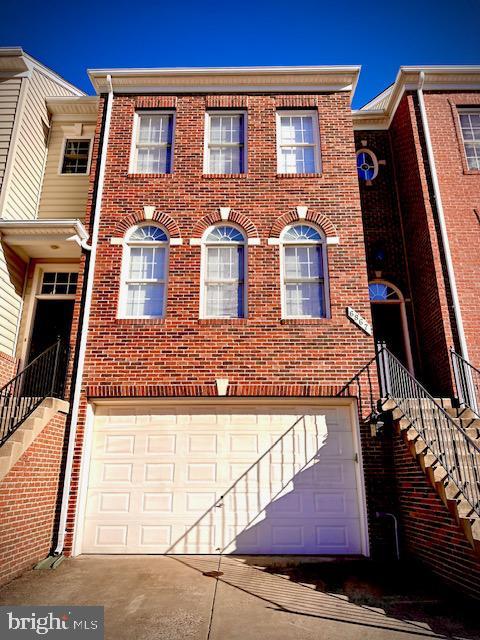 view of property with brick siding, stairs, and a garage