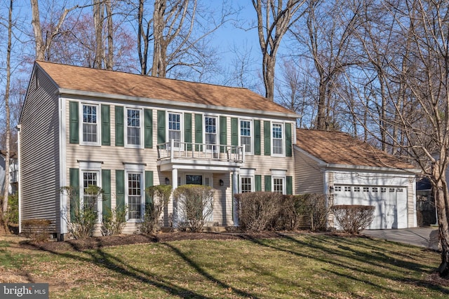 colonial house with a front lawn, a balcony, a garage, and driveway