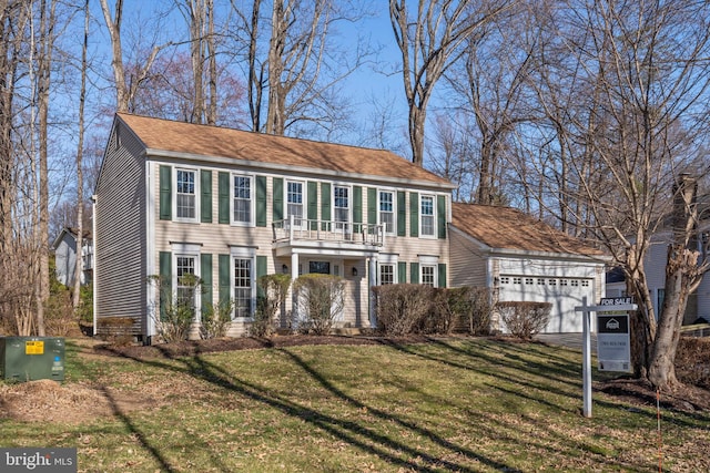 colonial home featuring aphalt driveway, a balcony, an attached garage, and a front yard