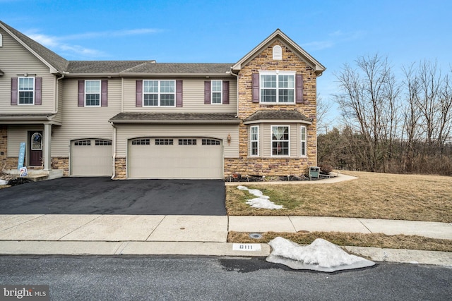 view of front facade featuring an attached garage, cooling unit, stone siding, driveway, and a front lawn