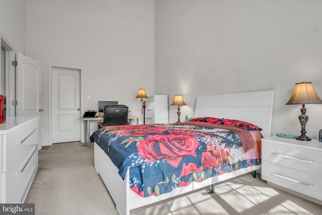 bedroom featuring a towering ceiling and light colored carpet