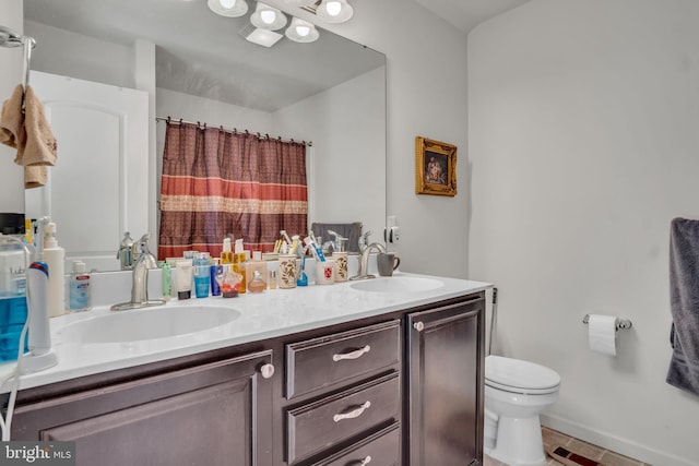 full bath featuring toilet, curtained shower, double vanity, and a sink