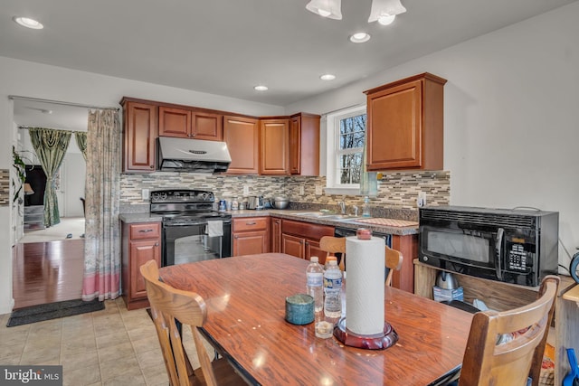 kitchen with backsplash, light tile patterned flooring, a sink, under cabinet range hood, and black appliances