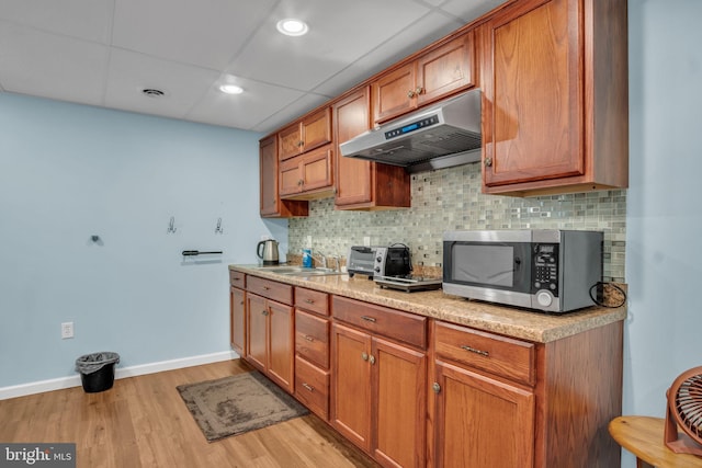 kitchen featuring tasteful backsplash, visible vents, stainless steel microwave, under cabinet range hood, and a sink