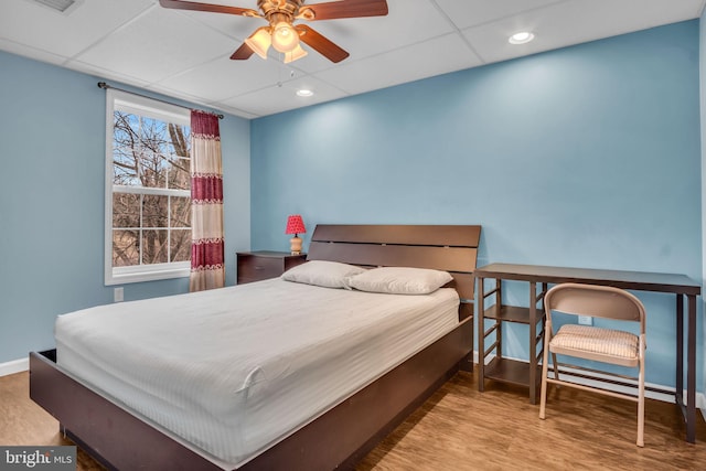 bedroom featuring recessed lighting, wood finished floors, a paneled ceiling, and baseboards