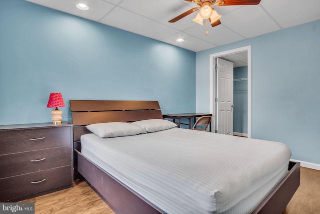 bedroom with ceiling fan, baseboards, a paneled ceiling, and light wood-style floors