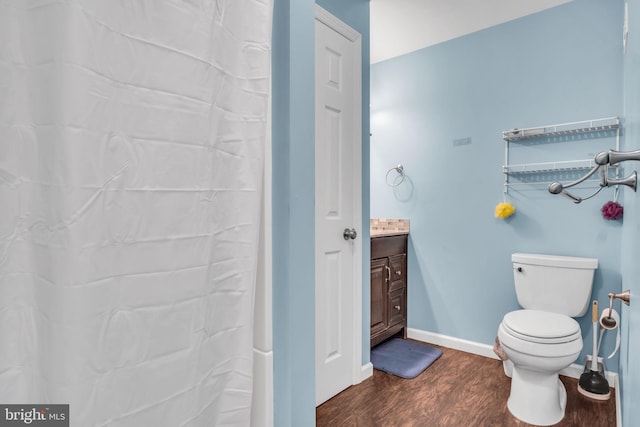 bathroom with toilet, wood finished floors, vanity, baseboards, and a shower with curtain