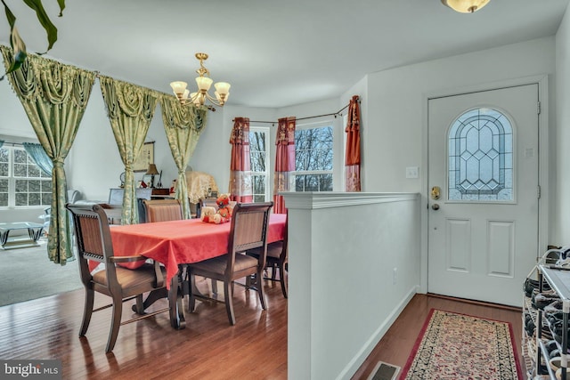 dining room with baseboards, wood finished floors, visible vents, and a notable chandelier