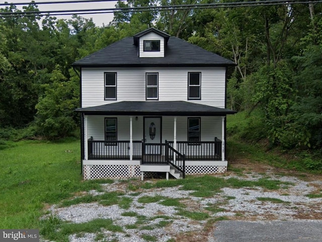 view of front facade featuring a forest view, a porch, and a front lawn